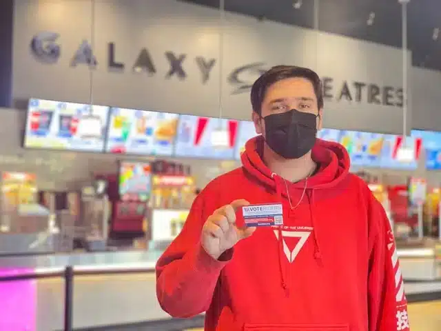 A moviegoer At Galaxy Theaters in Arizona holds up a VoteRiders voter ID information card 